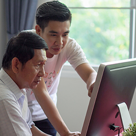 Young man teaching computers to senior man